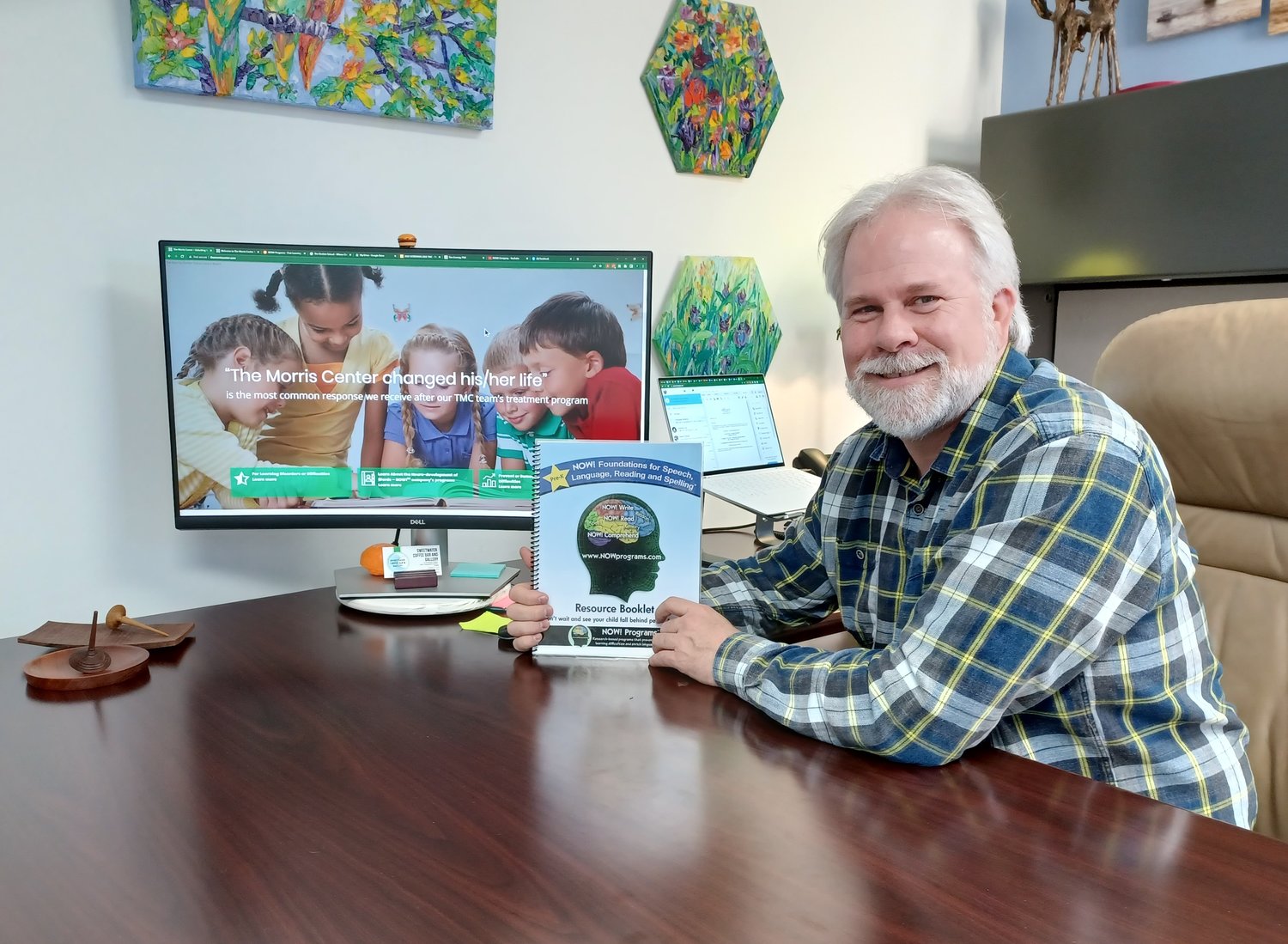 Dr. Tim Conway is seen at his desk with his resource booklet for “NOW! Foundations for Speech, Language, Reading and Spelling.”